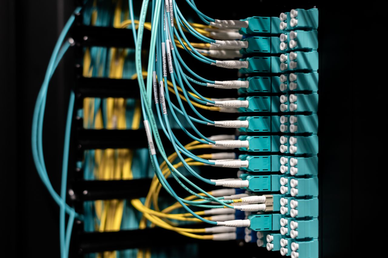Services Closeup of electronic device with colorful wires installed in rows in communications room on blurred background in dark studio inside